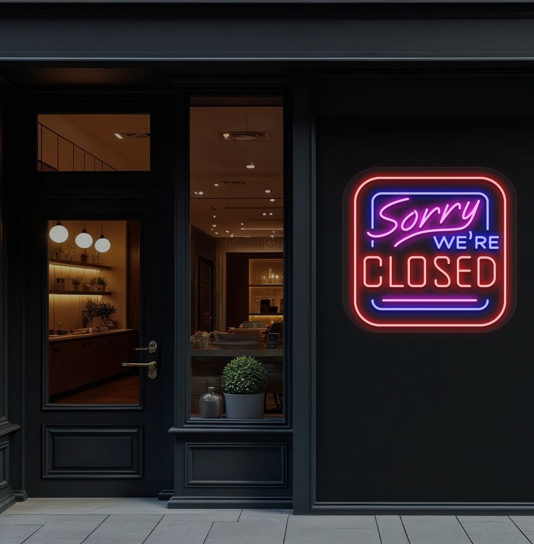 Image of a "Sorry, We're Closed" neon sign glowing on a shop exterior wall in red color.
