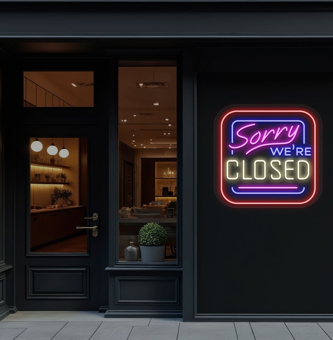 Storefront wall with sorry we're closed neon sign glowing warm white. 
