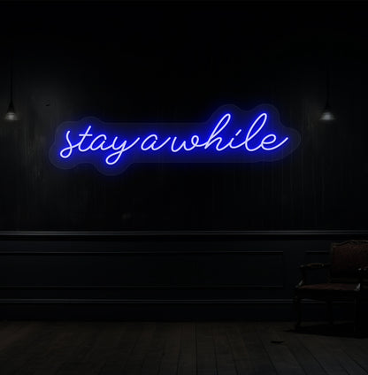 Image of a "stay a while" LED neon sign hanging on a wooden wall in blue color. 