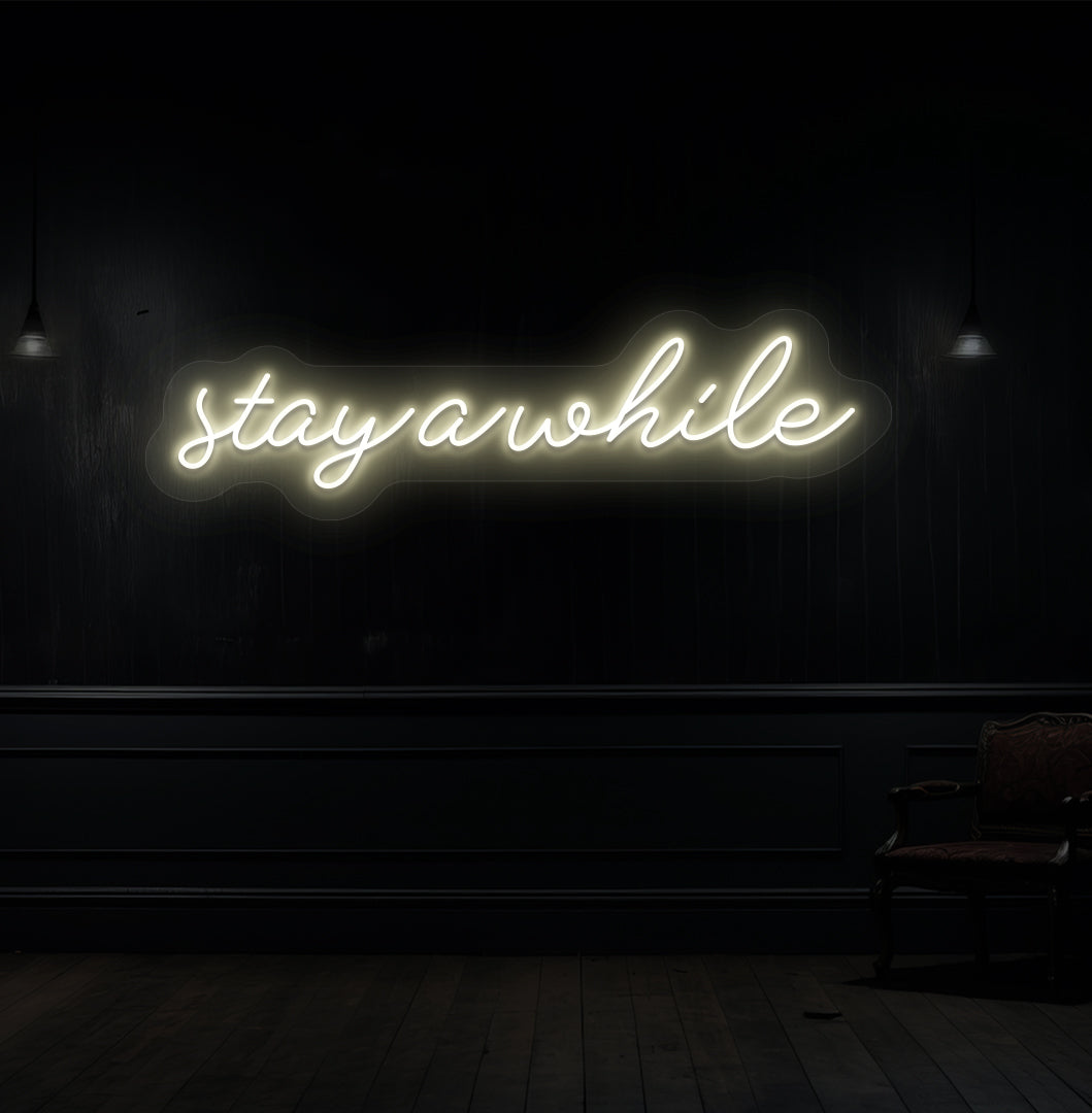 Decorative warm white neon sign "stay a while" on a wood panel wall. Perfect for living room & hallway décor, cafés, lounges, and reception spaces.