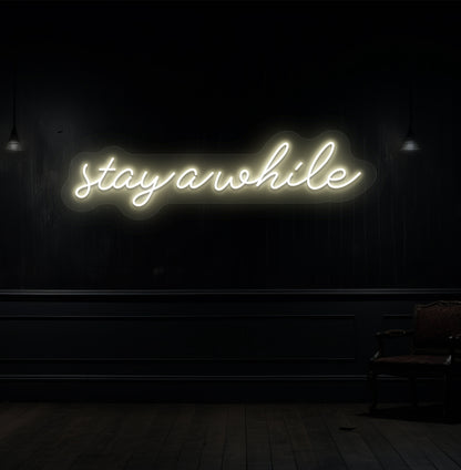 Decorative warm white neon sign "stay a while" on a wood panel wall. Perfect for living room & hallway décor, cafés, lounges, and reception spaces.