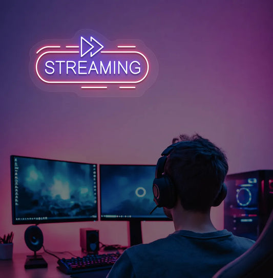Image of a "streaming" neon sign in blue color mounted on gaming room wall.