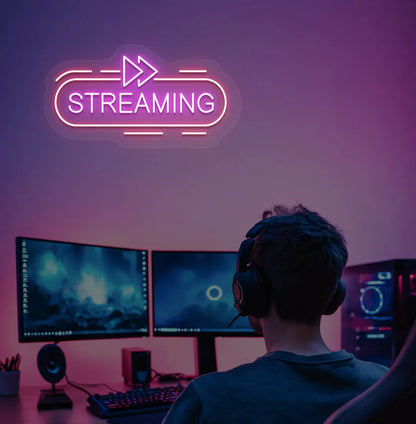 Image of a "streaming" neon sign in pink color mounted on gaming room wall.