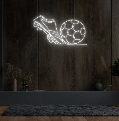 Image of a "Football with shoe" neon sign glowing white on sports-themed wall.