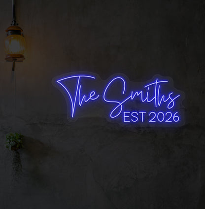 Image of "the Smiths" LED neon sign glowing on wall in blue.