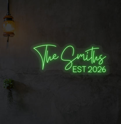 Custom name LED neon sign "The Smiths" glowing green on wall.