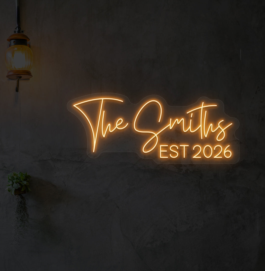 Custom name LED neon sign "The Smiths" glowing orange on wall.