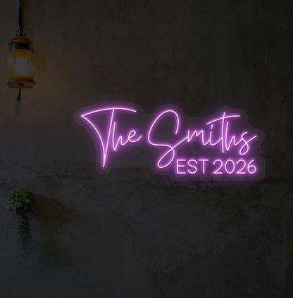 Custom name LED neon sign "The Smiths" glowing purple on wall.