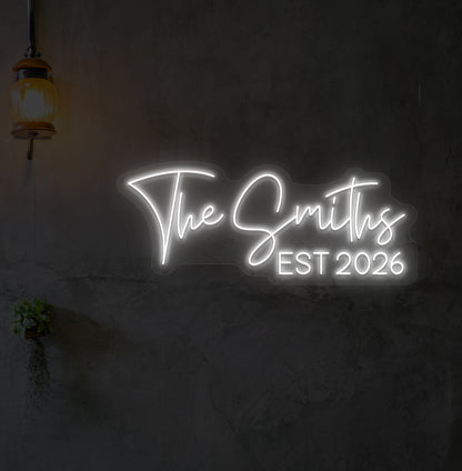 Image of "the Smiths" LED neon sign glowing on wall in white.