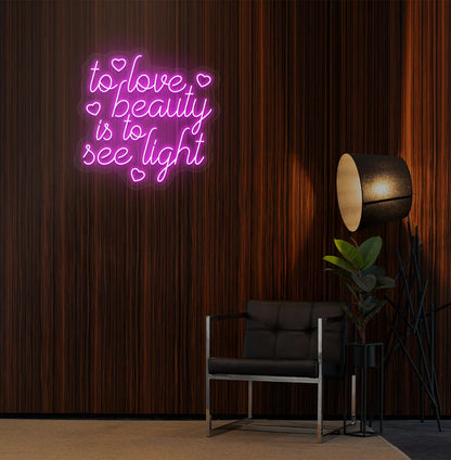 Image of a "To love beauty is to see light" neon sign in pink color on salon wall decor.