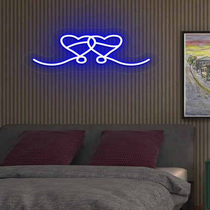 A blue LED two-hearts neon sign glowing on a romantic bedroom wall.
