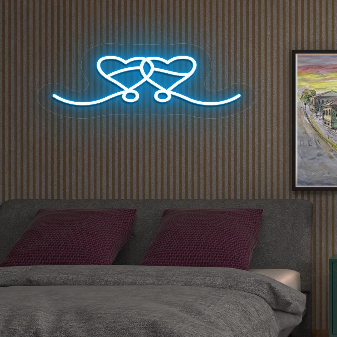 An image depicting a neon sign in the shape of two hearts, illuminated in ice blue, on the bedroom wall.
