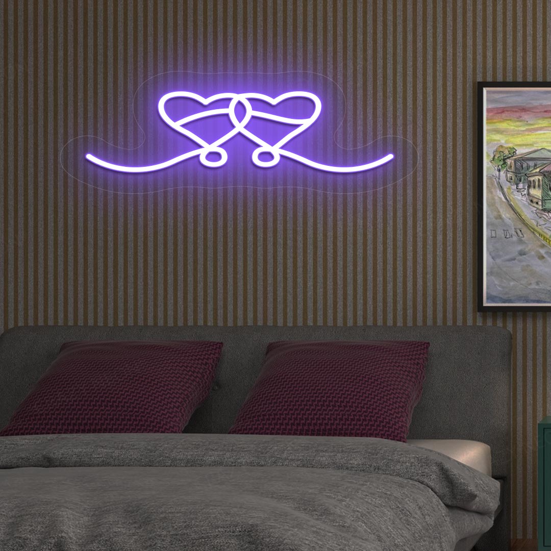 A purple LED two-hearts neon sign glowing on a romantic bedroom wall.