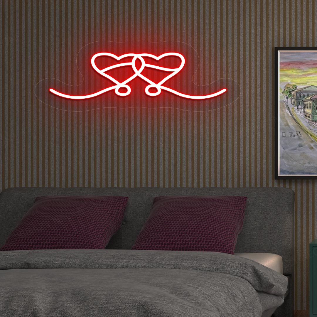 An image depicting a neon sign in the shape of two hearts, illuminated in red, on the bedroom wall.
