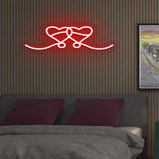 An image depicting a neon sign in the shape of two hearts, illuminated in red, on the bedroom wall.
