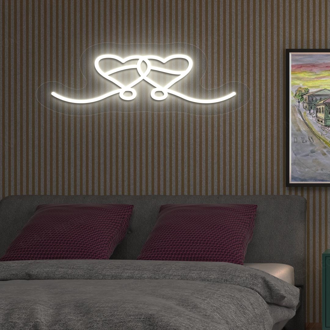 A warm white LED two-hearts neon sign glowing on a romantic bedroom wall.