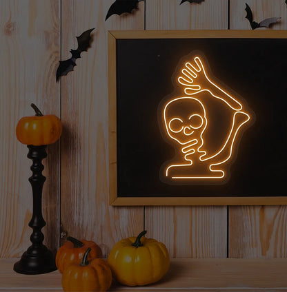 Waving Skeleton Orange Neon Sign creating a spooky glow on a Halloween themed wall.