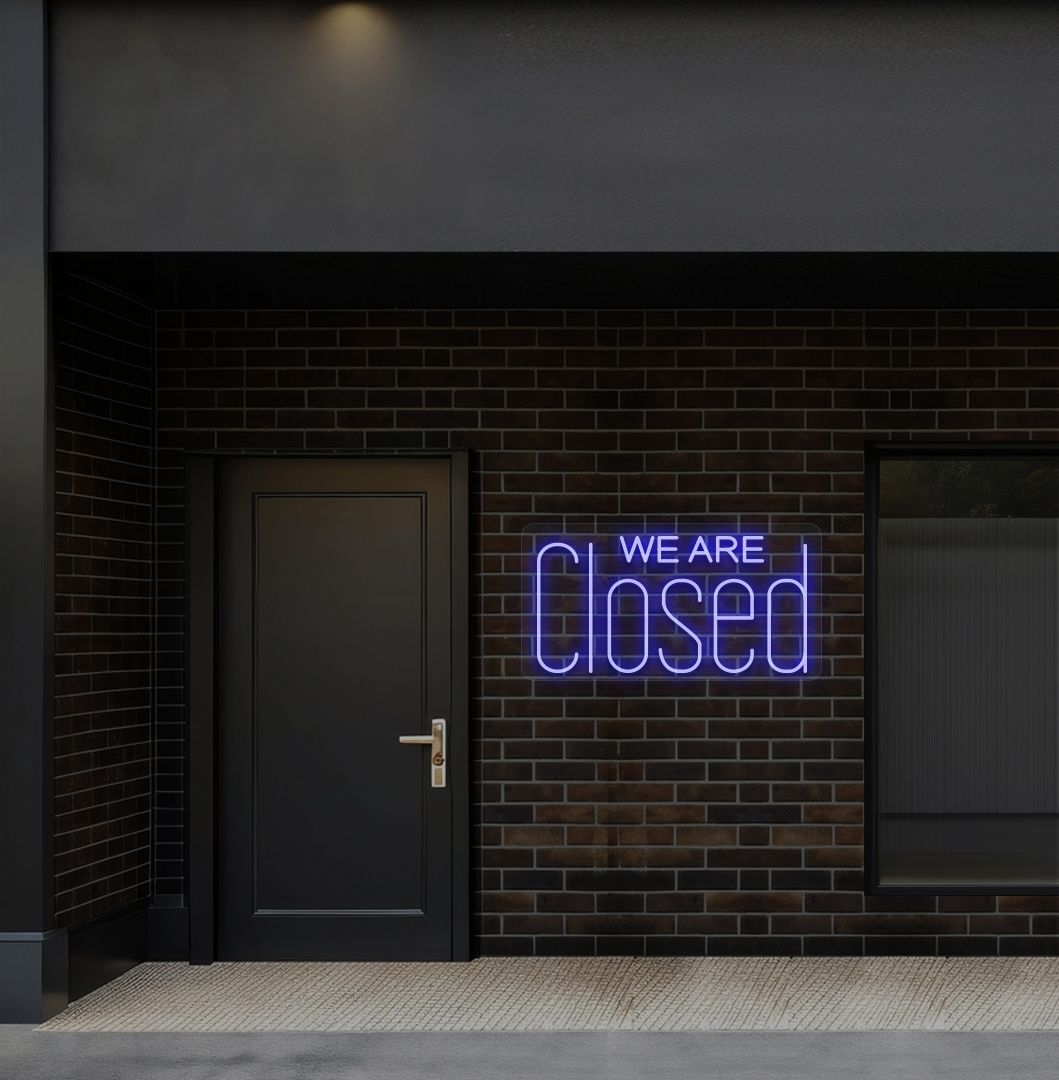 Image of a we are closed LED neon sign glowing on shop exterior wall in blue color.