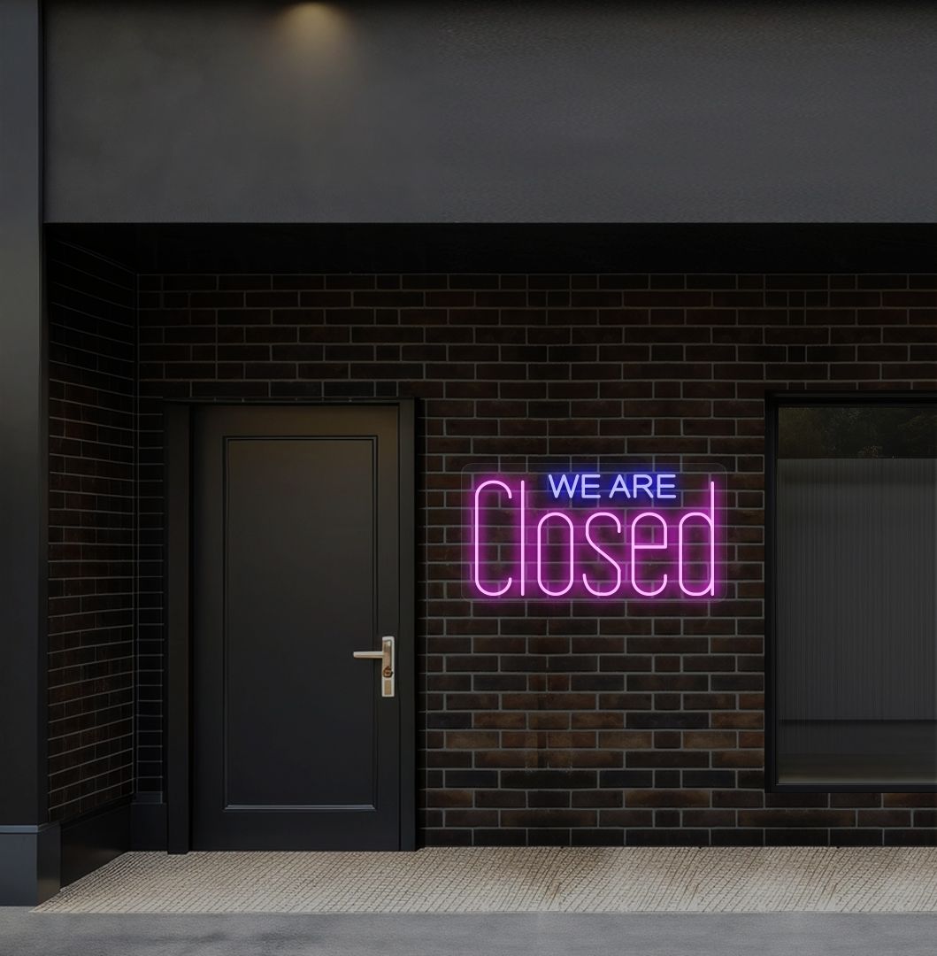 Image of a we are closed LED neon sign glowing on shop exterior wall in pink color.