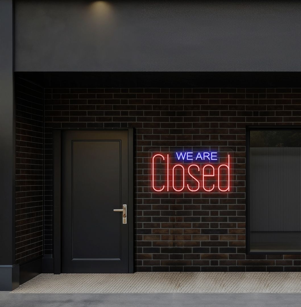 Image of a we are closed LED neon sign glowing on shop exterior wall in red color.