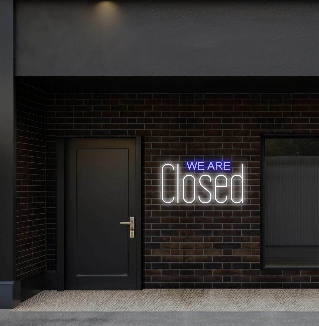 Image of a we are closed LED neon sign glowing on shop exterior wall in white color.