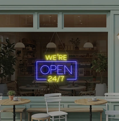 Stylish We Are Open 24/7 neon sign mounted on coffee shop glass door in blue color.