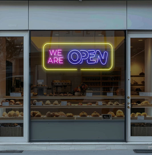 Image of a "We Are Open" neon sign glowing on the bakery door in blue color.