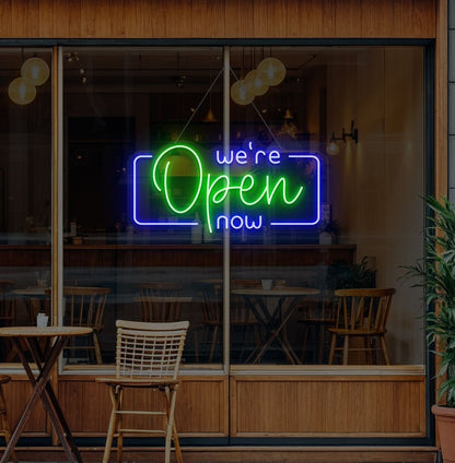 Modern we're open now neon sign glowing green on cafe door.