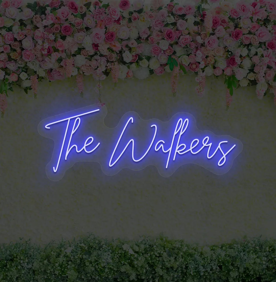 Personalized wedding name neon sign glowing blue on wedding backdrop.