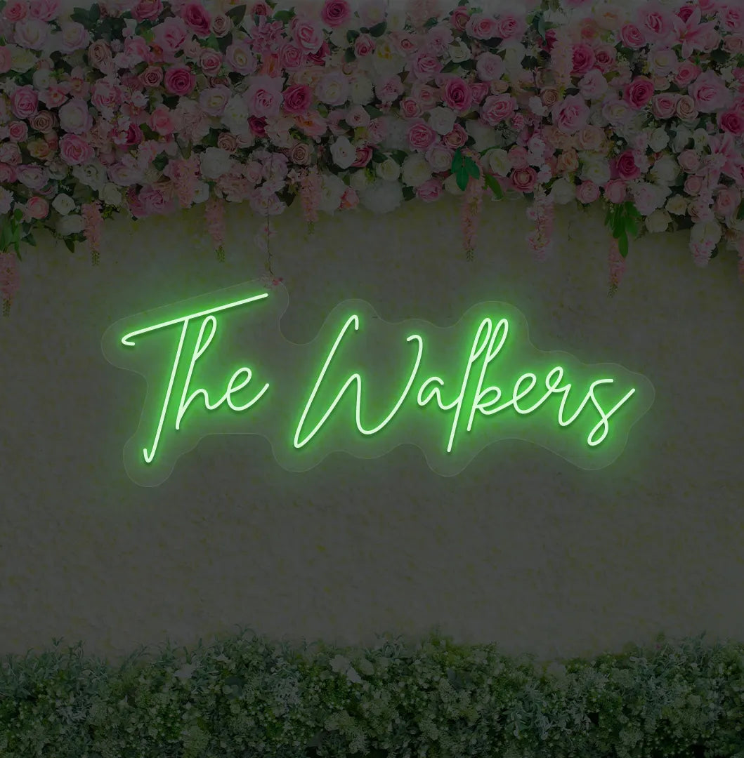 Image of a wedding name neon sign glowing green on decorative wall.