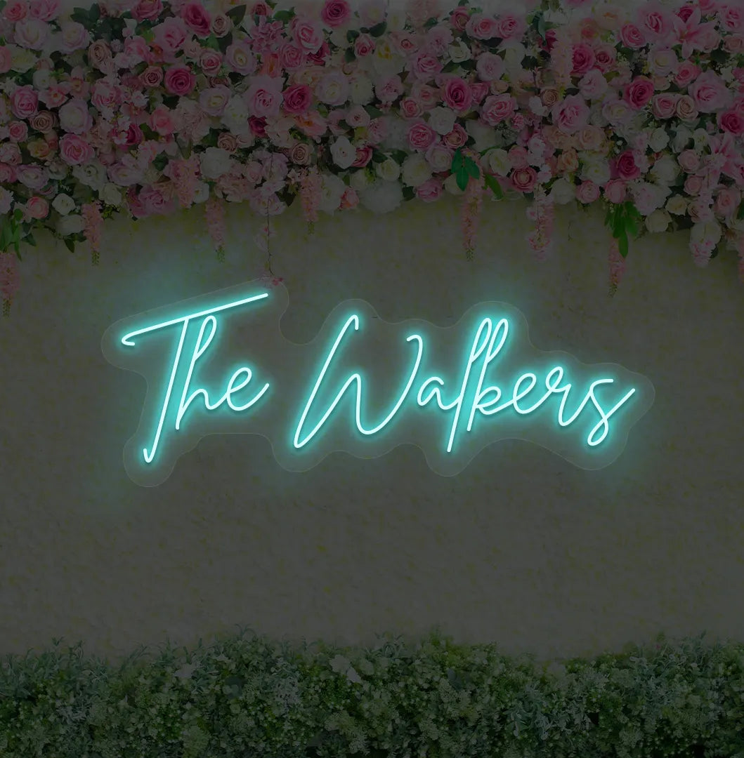 Personalized wedding name neon sign glowing ice blue on wedding backdrop.