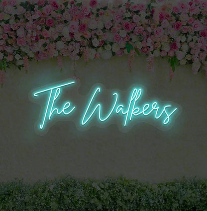 Personalized wedding name neon sign glowing ice blue on wedding backdrop.