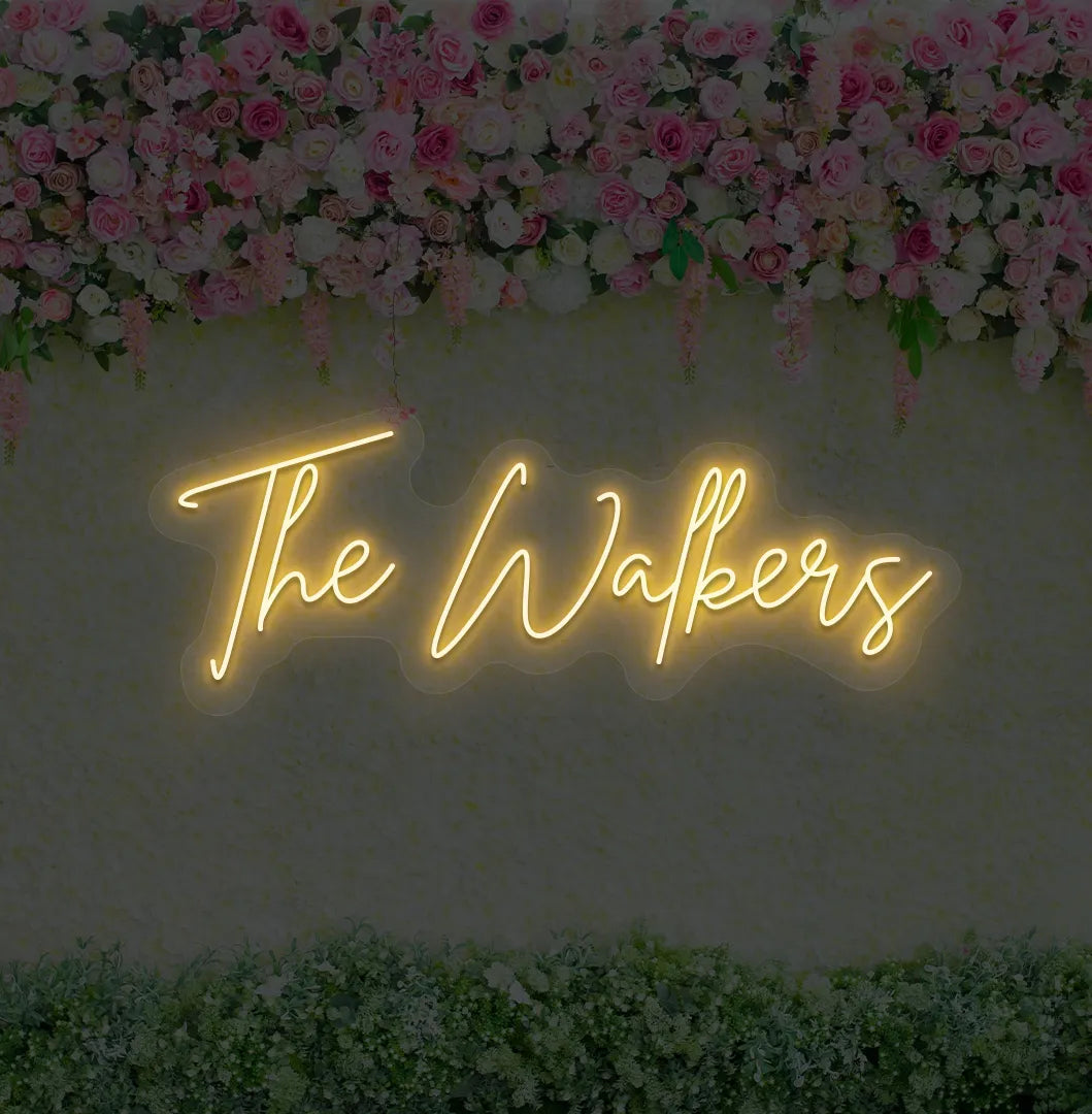 Image of a wedding name neon sign glowing orange on decorative wall.