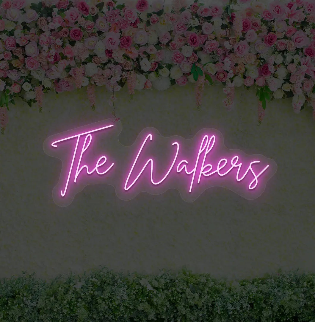 Image of a wedding name neon sign glowing purple on decorative wall.