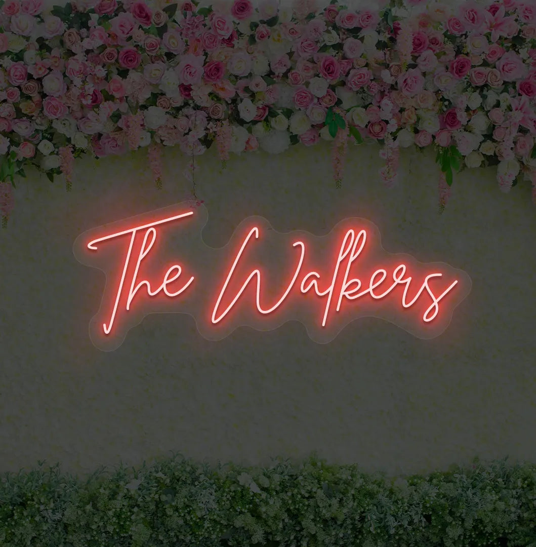 Personalized wedding name neon sign glowing red on wedding backdrop.