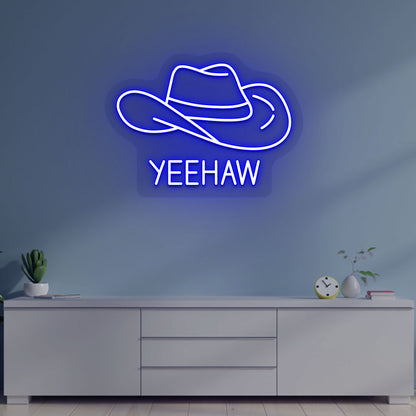 Image of a "YEEHAW" neon sign with a cowboy hat on a living room wall in blue color. 