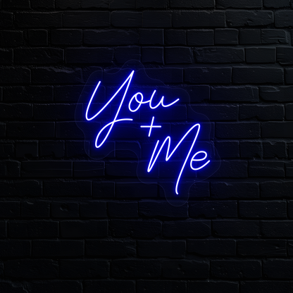 Image of a "you plus me" LED neon sign glowing on wall in blue.