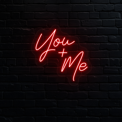 Image of a "you plus me" LED neon sign glowing on wall in red.