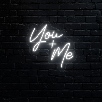 Image of a "you plus me" LED neon sign glowing on wall in white.
